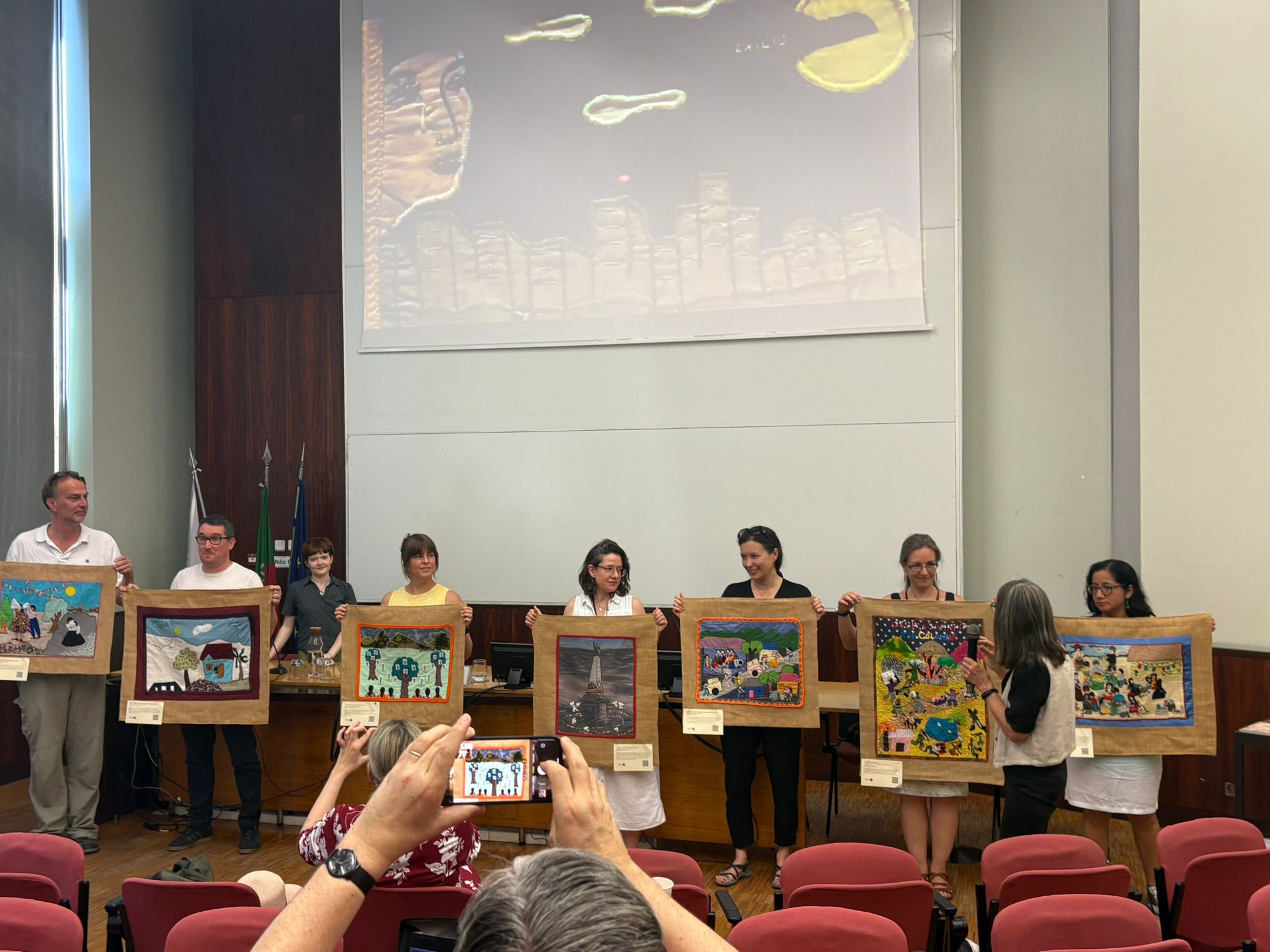 Colleagues holding the 7 arpilleras presented July 4 at Conflict Textiles plenary (Photo: Slow Memory archive)